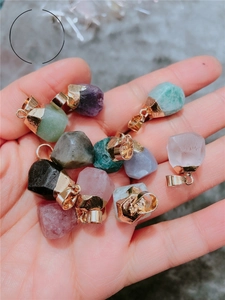 Detailed macro view of raw gemstone pendants held in hand to showcase small scale and texture