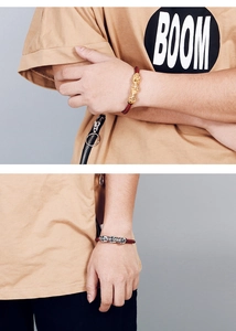 Close-up of men's red braided leather bracelet with gold and silver skull charms