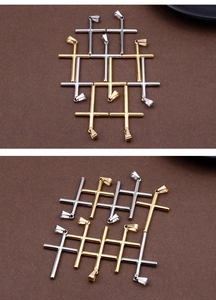 Detailed view of polished gold and silver stainless steel cross charms on dark surface