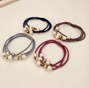 Detailed view of four elastic hair ties with pearls in navy, coffee, grey, and red colors