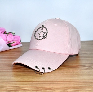 Pink cotton baseball cap with star metal ring and brim rings on a wooden desk