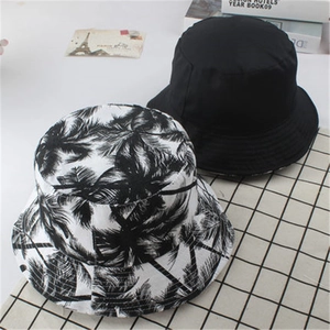 Double-sided reversible bucket hat in solid black and tropical palm tree print pattern