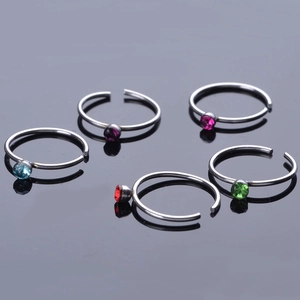 Detail of colorful crystal inlaid stainless steel nose rings on a reflective black base