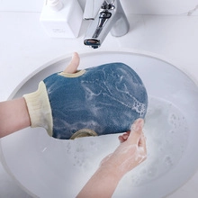 Primer plano de un guante de baño exfoliante azul con abundante espuma de jabón.