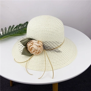 Detailed shot of cream straw sun hat featuring elegant champagne fabric flowers and veil