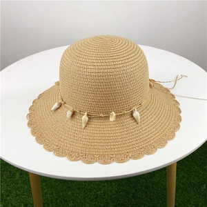Chapeau de paille avec détails en coquillages et bord ondulé pour vacances à la plage