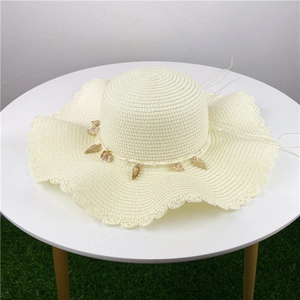 Chapeau de paille crème à bord ondulé et breloques en coquillages pour plage et soleil