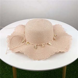 Chapeau de paille beige avec breloques coquillages et bord ondulé pour la plage d'été