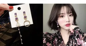 Detailed view of asymmetric gold-tone long fringe earrings with purple stones on model