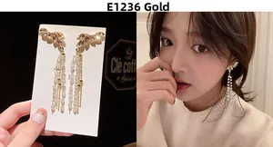Detailed close-up of gold tassel earrings with leaf-shaped rhinestones and long bead chains