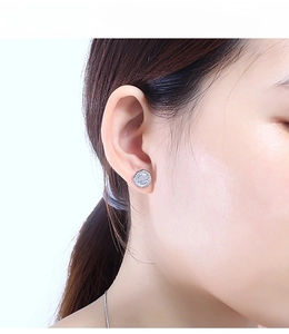 Close-up of silver-toned relief portrait stud earrings worn by a model in profile