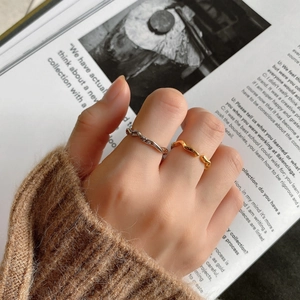 Close-up of minimalist wavy silver and gold rings worn with a stylish fall sweater