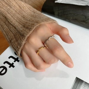 Close-up of wavy minimalist 925 sterling silver rings in gold and silver finish