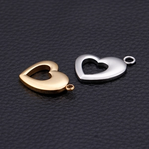 Polished gold and silver heart-shaped stainless steel pendants on black leather surface