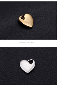 Polished hollow heart charms in gold and silver steel finishes on black leather texture