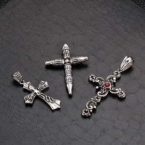 Three vintage gothic stainless steel cross pendants with red gemstone on black background