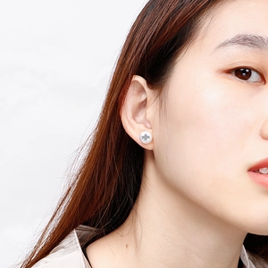 Minimalist stainless steel pearl earrings with gray cross inlay on female model