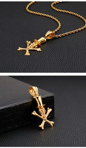 Detail of a gold punk skull pendant with top hat and crossbones on black leather background