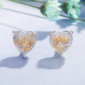 Elegant heart-shaped stud earrings with gold foil accents on a blue floral background