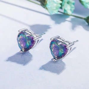 Elegant heart-shaped rainbow opal stud earrings with silver four-prong setting on blue fabric