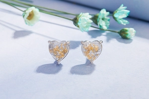 Macro shot of heart-shaped opal studs with silver metal and gold foil inlay details