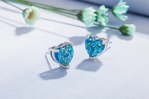 Detailed macro view of heart-shaped silver earrings with vibrant blue opal inlays