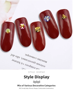 Detailed view of geometric metal studs and colorful rhinestones on deep red DIY nail art
