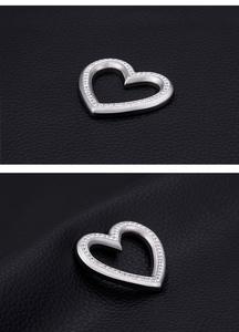 Macro shot of silver heart pendant with crystals on black leather background