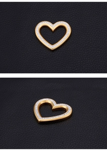 Detailed view of a gold-plated heart pendant with sparkling crystals on black leather