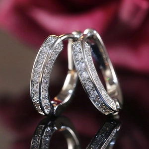 Macro detail of U-shaped silver hoop earrings with pavé set white zircon stones