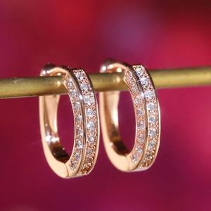 Macro shot of rose gold hoop earrings with multi-row pavé setting and sparkling crystals