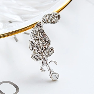 Sparkling silver crystal feather brooch pin on a decorative glass tray for elegant style