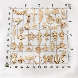 Variety of gold alloy charms for DIY jewelry making on a measuring ruler background