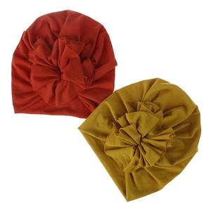 Detail of high-elasticity baby turbans with large pleated flowers in red and yellow