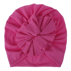 Detail of rose pink baby turban hat featuring a large layered pleated flower design