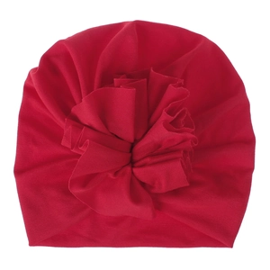 Detail shot of the large ruffled flower decoration on the soft red baby turban hat.