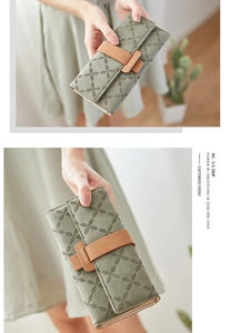 Close-up of grey-green long wallet with clover embossing and metal branding buckle