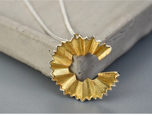 Detailed close-up of a creative S925 silver pencil shaving pendant with gold interior