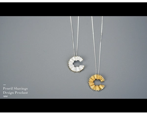 Macro shot of gold and silver pencil shavings pendant with delicate fine chain