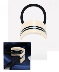 Detail view of cream acetate hair tie with black stripes measuring 2 by 3.8 cm