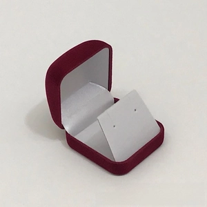 Close-up of a small burgundy velvet jewelry box with white satin lining and earring card