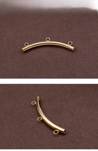 Macro detail of curved gold plated connector tube with three hanging loops for jewelry DIY