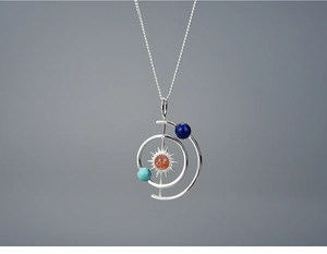 Macro shot of solar system necklace with sunstone pendant and planetary orbit detail