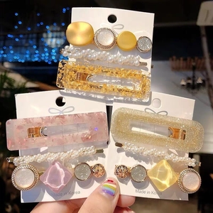 Close-up of geometric acetate hair clips with gold, resin, and pearl accents