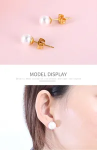 Vue détaillée des boucles d'oreilles perles blanches rondes sur base dorée