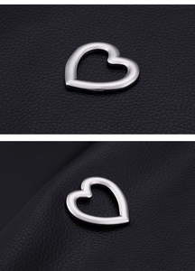Polished silver heart-shaped stainless steel charms on black leather background