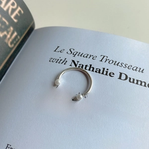 Detailed view of an S925 sterling silver smile ring with pearls on an open book