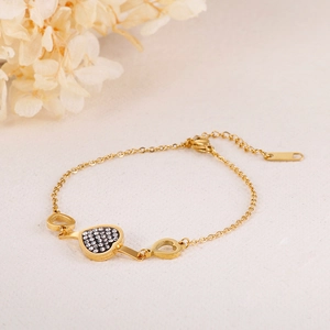 Elegant gold heart bracelet for women with black crystals on a minimalist background