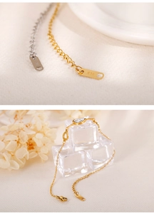 Macro shot of 14K hallmark on gold bracelet clasp extension over ice background