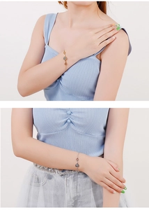 Close-up of heart grid pendants on gold and silver chain bracelets worn by a model